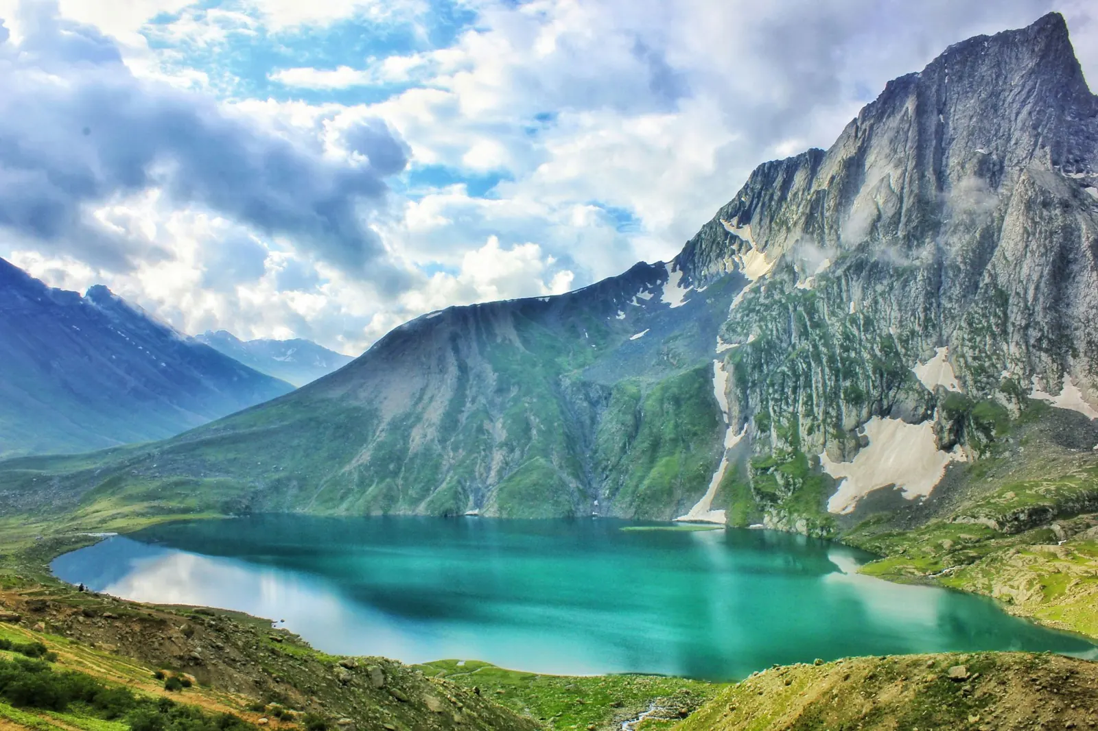 Turquoise alpine lake below a rocky peak in the Kashmir high mountains