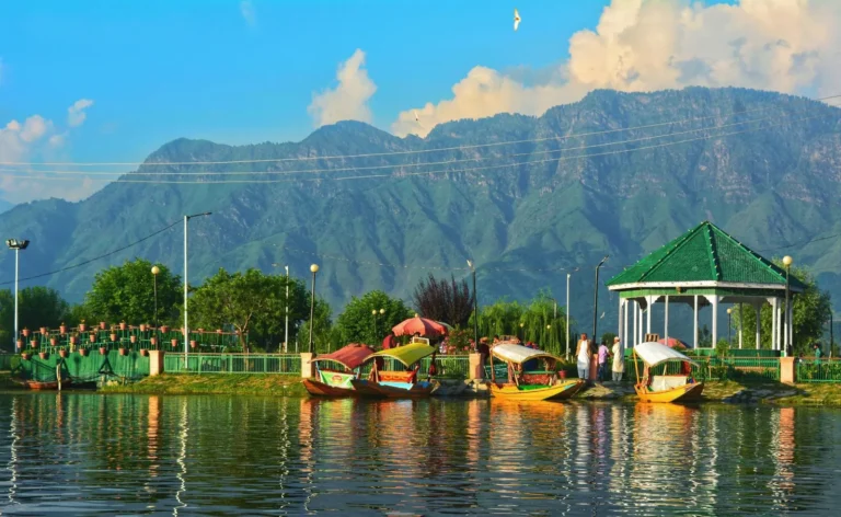Shikaras moored by a lakeside park on Dal Lake, Srinagar, with the Zabarwan mountains behind